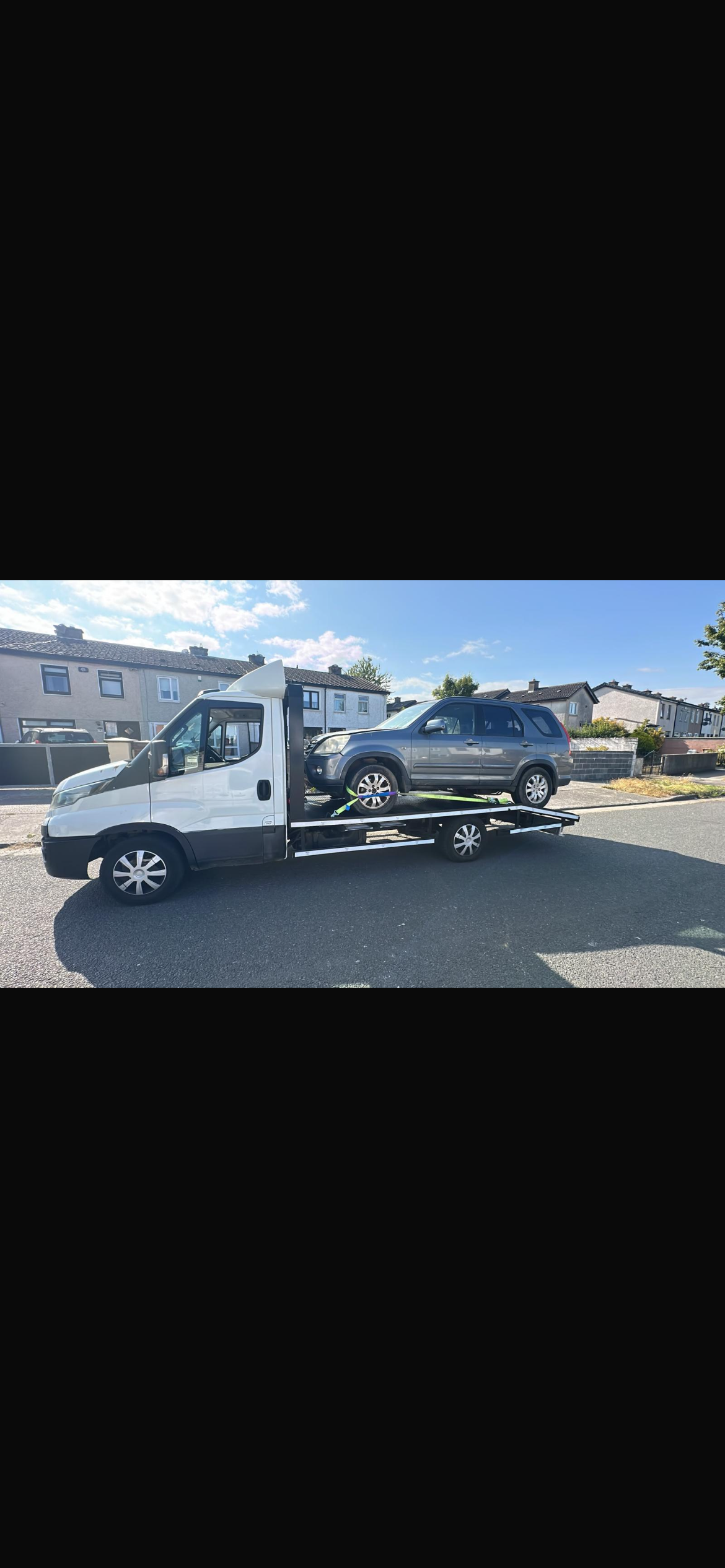 Flatbed tow truck carrying a car during roadside recovery operation