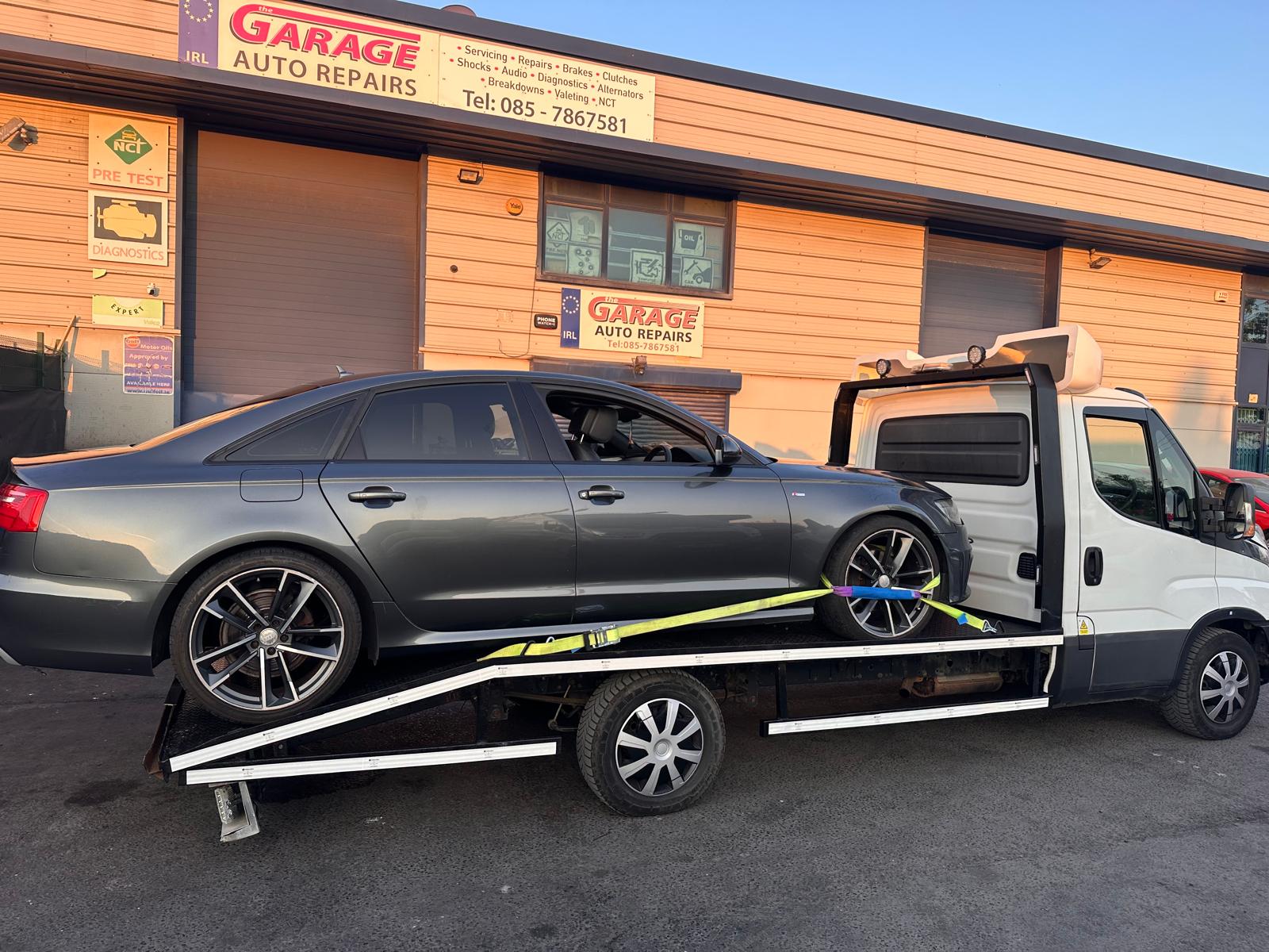 Scrap vehicle being secured on a hydraulic flatbed recovery truck