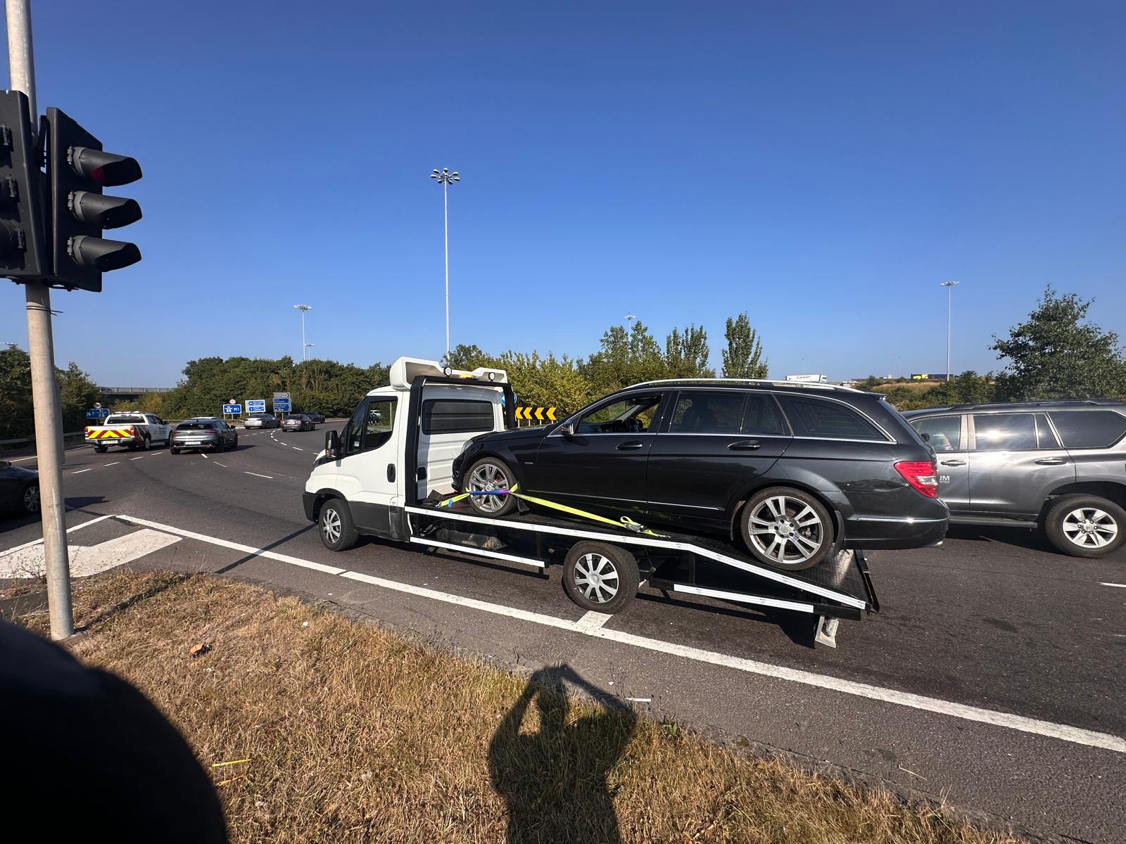 Professional flatbed recovery truck securely transporting a vehicle for roadside assistance